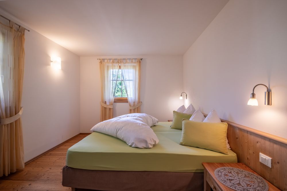 Ein gemütliches Schlafzimmer mit einem Doppelbett, in hellen Farben gehalten und mit Holzakzenten ausgestattet.