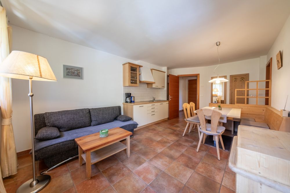 A cozy living area with an open kitchen, small sofa, and dining table in a vacation apartment.